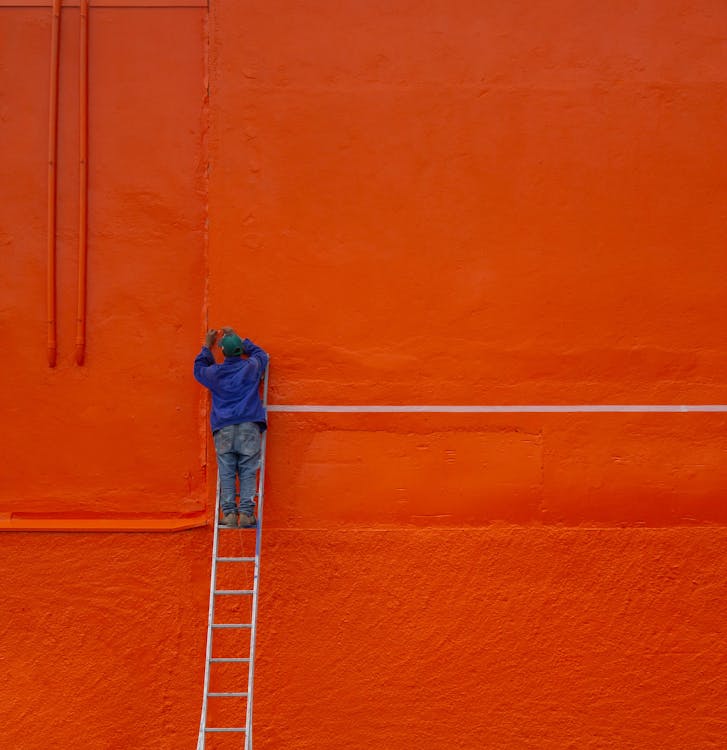 A person painting an exterior wall using weather-resistant paint