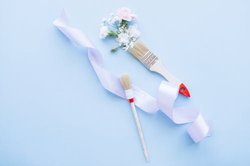 Paint brushes next to colorful flowers