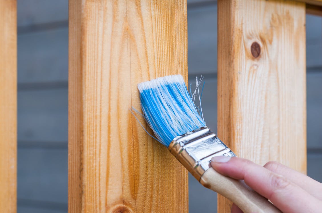 Person painting a fence with low-VOC exterior paint