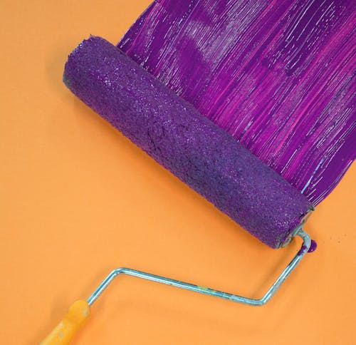 Paint roller being used to apply low-VOC purple paint