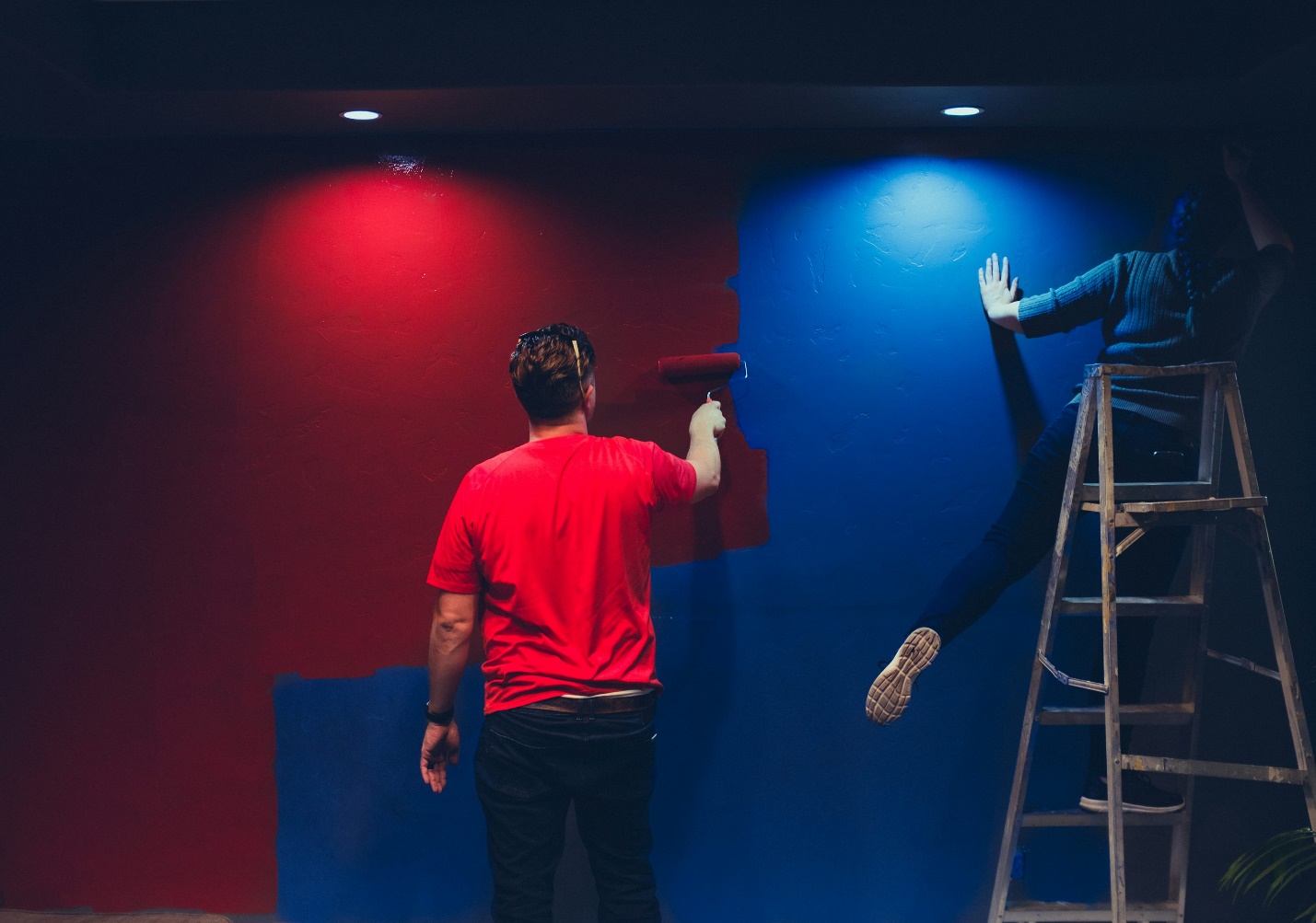 Two people painting a wall with different colors