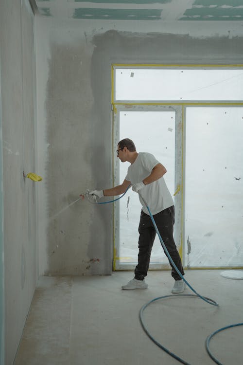 A person painting a wall with a spray