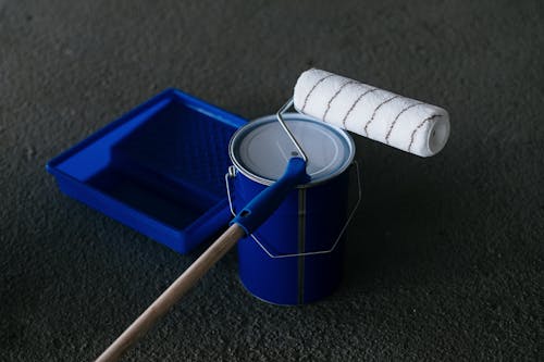 A paint roller resting on a paint can.