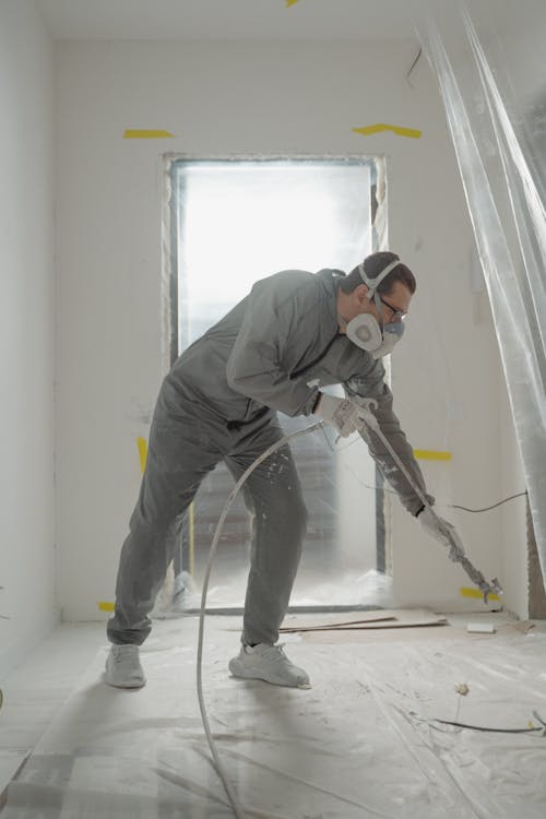 A professional painter wearing a mask while applying paint to an interior wall for a larger.