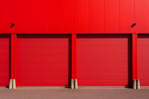 Red garage doors on a commercial building, freshly painted to highlight a vibrant and professional finish.