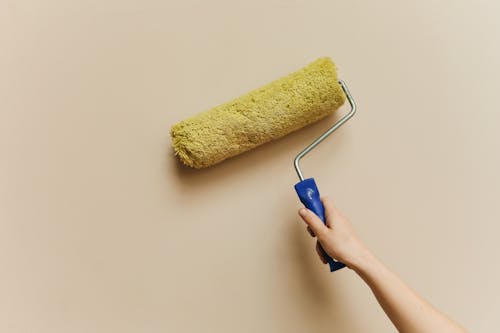 Close-up of a paint roller applying even coats of paint on a wall during an interior painting project.