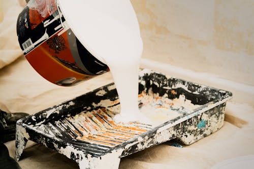 A professional pouring paint into a container, preparing for residential and commercial painting work.