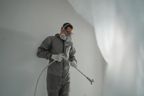 A professional painter holding a paint sprayer, demonstrating expertise in achieving a flawless finish on commercial painting projects.