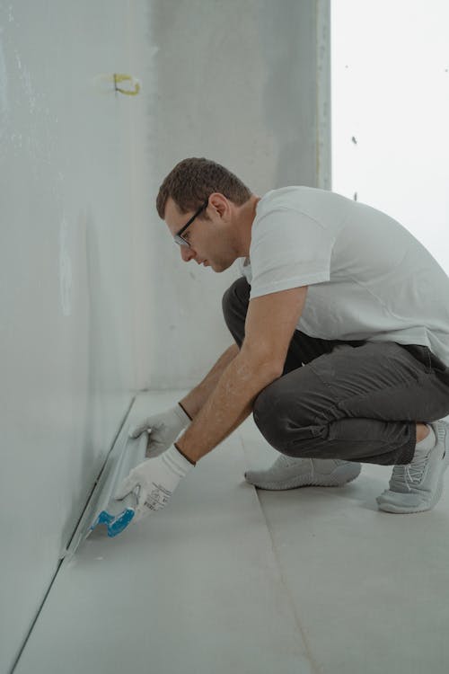 A professional painter working on a residential or commercial project with tools in hand.