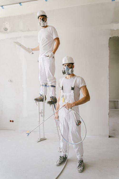 A group of professional painters wearing uniforms and working on a large-scale painting project.