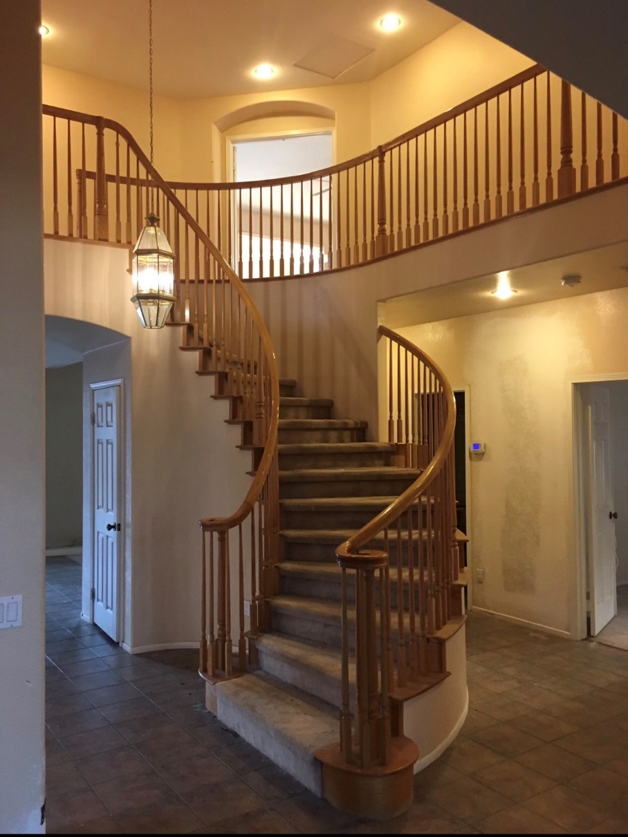 A before picture of a staircase with light brown railings