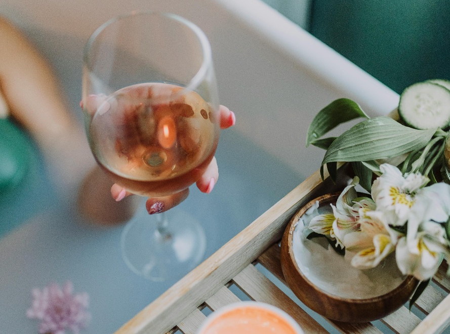 Person holding a beverage while sitting in a bathtub