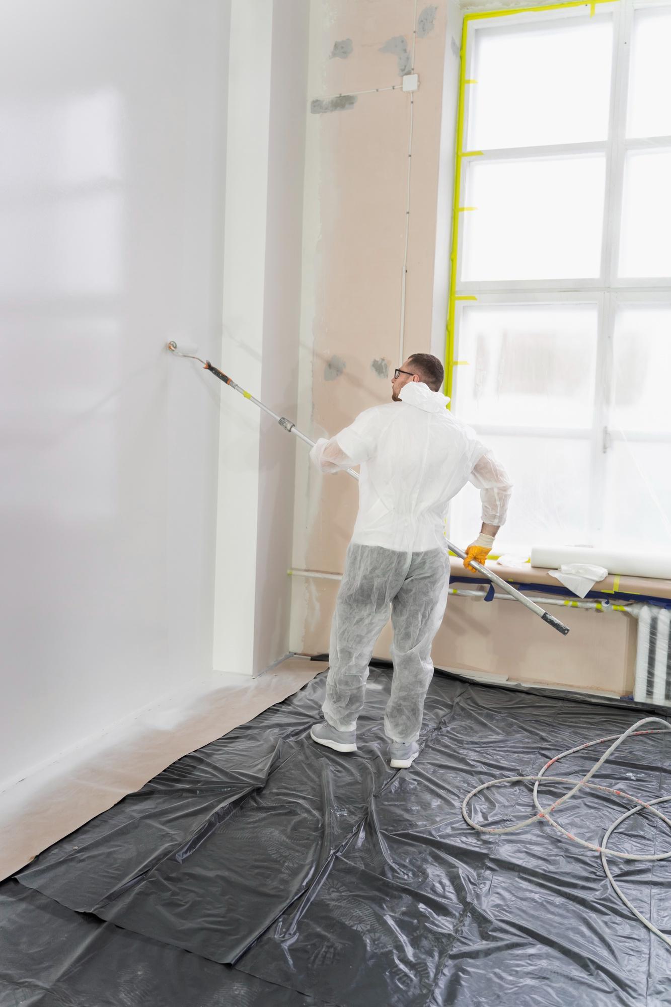 Person applying fresh paint to an interior wall to enhance the look of a commercial space.