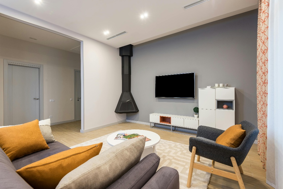 A charcoal grey chair placed next to a sofa with throws 